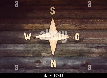 Wooden compass on a wooden wall in a country house. Decorated wall in the form of a compass, indicating the parts of the world North, South, West, Eas Stock Photo
