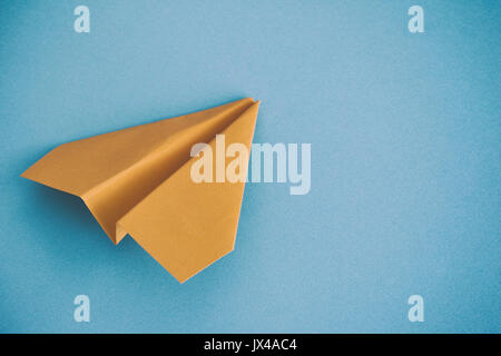 Yellow paper plane on a blue background. Close up. Stock Photo