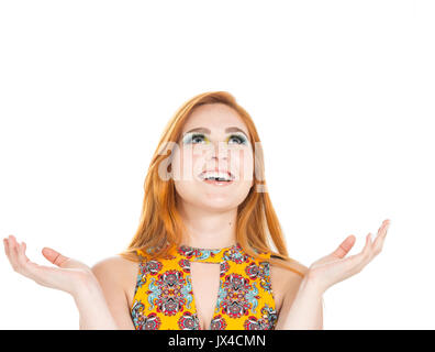 It's a lot of happiness for this young girl. She gestures and looks up. Fashion and colorful makeup. Redhead teenager wears vibrant yellow dress and f Stock Photo