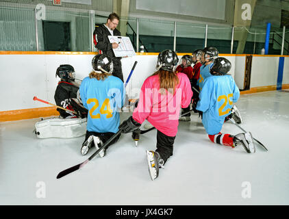A Hockey Coach at practice teaches game plan to team players Stock Photo