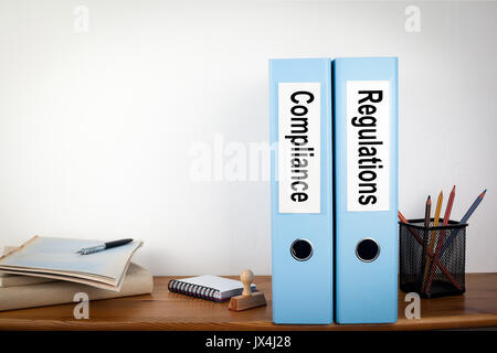 Compliance and Regulations binders in the office. Stationery on a wooden shelf. Stock Photo