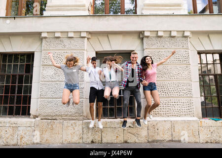 Group attractive teenage students in front of university jumping high. Stock Photo