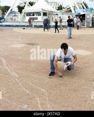 Pier Approach, Bournemouth, Dorset, UK, 14th August 2017. Adjacent to the pier, artists begin work on a large street art painting hosted by Ambassadeur Art. The chalk outline sketches reveal the piece as being of the Spiderman superhero character which, when complete, will be best viewed from the top of the ferris wheel ride in front of which it lies. Stock Photo