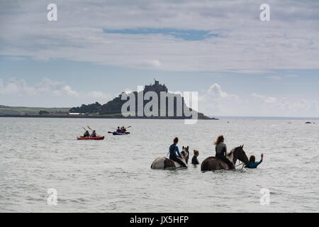 Longrock, near Marazion, Cornwall, UK. 15th August 2017. UK Weather.  The sunshine came out for Mea Sucato who flew from New York to Cornwall for her birthday treat of swimming in the sea with Cornwall swimming horses at Marazion. Mea on the horse on the right in front of St Michaels Mount Credit: Simon Maycock/Alamy Live News Stock Photo
