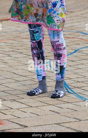 Artists colourful apron and leggings with novelty socks - artist at  Bournemouth, Dorset UK Stock Photo - Alamy