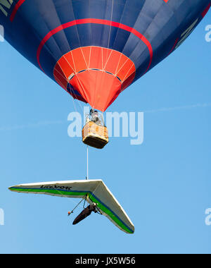 A hang glider suspended from the Royal Navy balloon, one of over 130 launched at dawn from Ashton Court park at the 39th Bristol Ballon Fiesta 2017