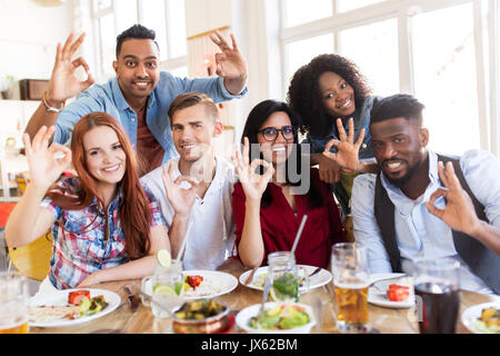 happy friends showing ok hand sign at restaurant Stock Photo
