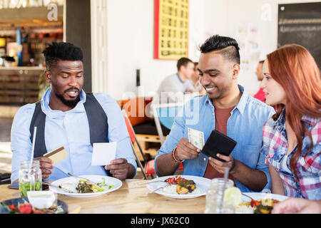 happy friends paying bill for food at restaurant Stock Photo