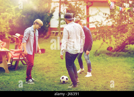 happy friends playing football at summer garden Stock Photo