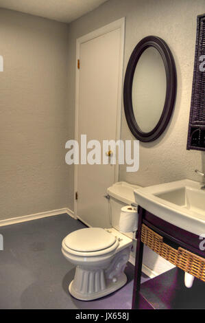 Small interior bathroom in a home that is clean and clutter free.  Vertical with no people. Toilet, sink and mirror on wall. Stock Photo