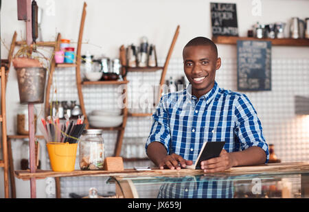 Smiling young African entrepreneur working in his cafe Stock Photo