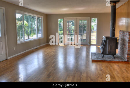 Residential family room of a home.  Room is empty with no furniture, a wood stove, French doors and hardwood floors. Stock Photo