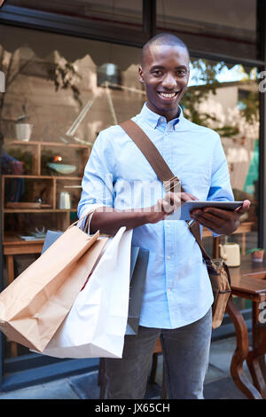 Young man using a tablet while shopping in the city Stock Photo