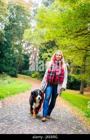 Woman walking the dog on leash in park Stock Photo