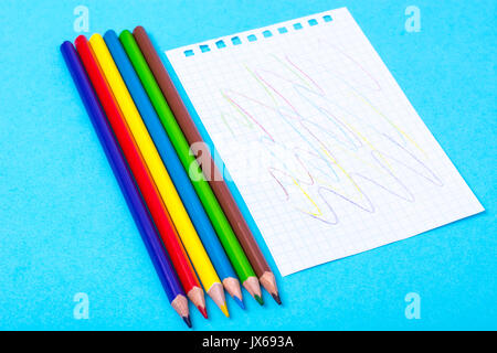 Notepad for notes and colorful pencils on colored background. Studio Photo Stock Photo
