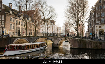 Tourist cruise boat in a canal in Amsterdam (Netherlands). March, 2015. Landscape format. Stock Photo
