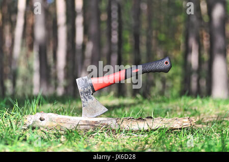 Tourist axe in wood outdoor. Chopping wood with ax. Ax stuck in a log of wood in the forest on nature background. Copy space of freedom, adventure, tr Stock Photo