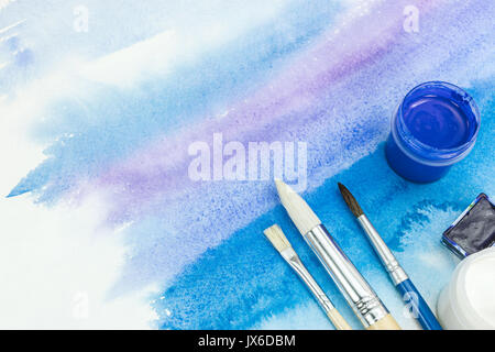 set of paints and paintbrushes on abstract watercolor hand drawn background Stock Photo