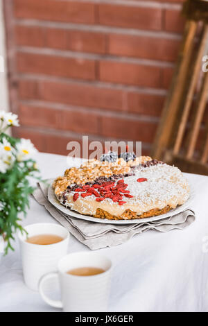 Raw vegan sweet carrot cake with cream topped with walnuts, goji berries, chocolate truffles, coconut flakes and cocoa crochet. Healthy homemade desse Stock Photo