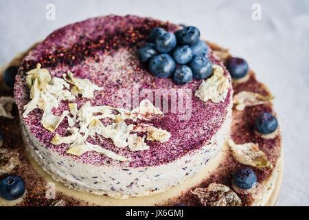 Raw blueberry cheesecake, homemade with decoration of dried flowers and fresh berries. Healthy handmade dessert. White background Stock Photo