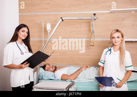 Patient in hospital room next to two nurses Stock Photo
