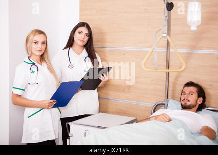 Patient in hospital room next to nurses Stock Photo
