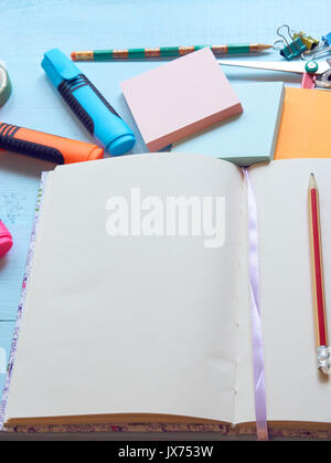 closeup of blank notebook with pencil, bookmark and stationery on background. sticky notes, scissors, vivid markers Stock Photo