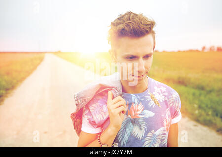 sad young hippie man walking along country road Stock Photo