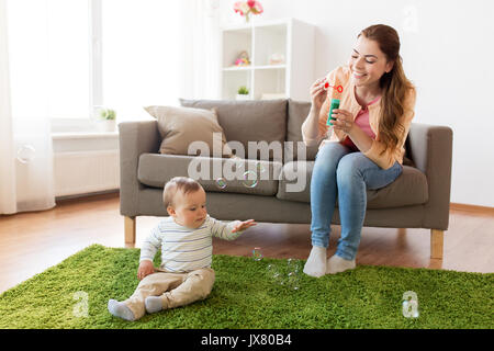 mother with soap bubbles playing with baby at home