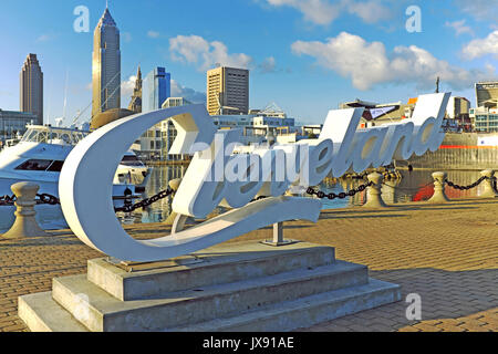 View from the Northcoast Harbour on Lake Erie of downtown Cleveland, Ohio, USA shows the dynamic skyline and in the foreground is the 'Cleveland' sign Stock Photo