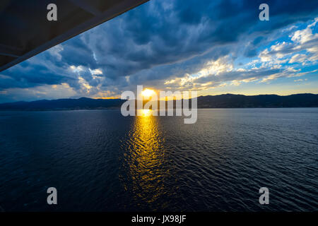 The sun going down from the balcony of a cruise ship on the Mediterranean Sea as a storm blows in Stock Photo