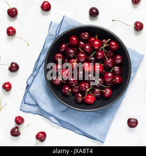 Sweet cherries in black bowl on bright grey background. Flat lay top view Stock Photo