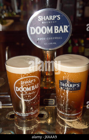 Two pints of Sharp's Doom Bar real English ale standing beside the hand pump and pump clip. Stock Photo