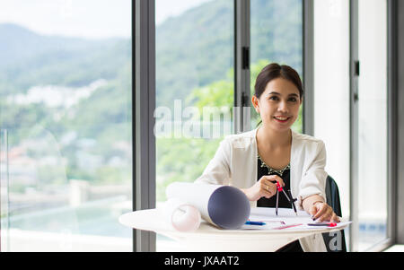 The female architects are using dividers and tools for idesign on the blueprints Stock Photo