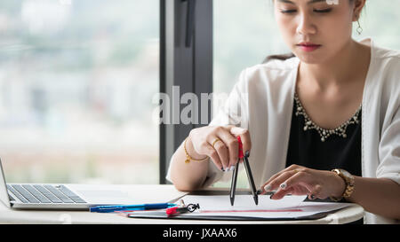 The female architects are using dividers and tools for idesign on the blueprints Stock Photo