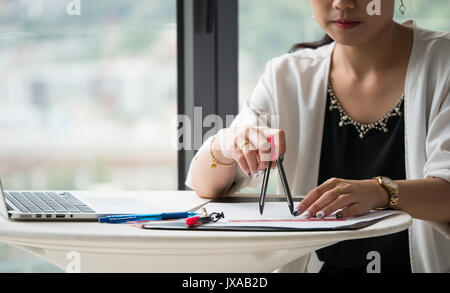 The female architects are using dividers and tools for idesign on the blueprints Stock Photo