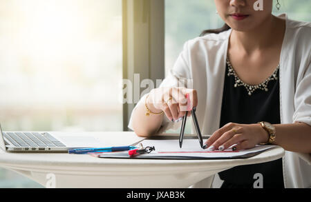 The female architects are using dividers and tools for idesign on the blueprints Stock Photo