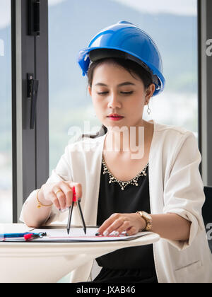 The female architects are using dividers and tools for idesign on the blueprints Stock Photo