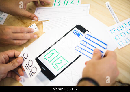 ui designers placing content on smartphone screen Stock Photo
