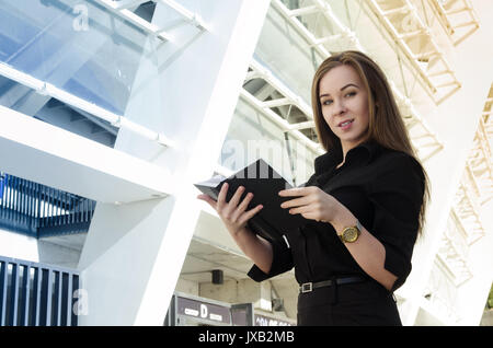 The beautiful businesswoman has a gold watch and a black notebook. Smiles at camera. Horizontal photo Stock Photo