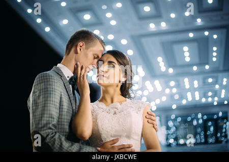 The bride and groom stand on the beautiful porch of the hotel at night Stock Photo