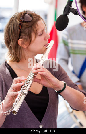Short haired Caucasian woman, 20s, playing flute. Side view, close up. Member of Jazz band Gator Dog Snappers. Stock Photo