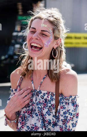 Beautiful blonde Caucasian teenage woman, laughing out loud outdoors. Close up of head and shoulders. Eyes closed, mouth wide open. Happiness. Stock Photo