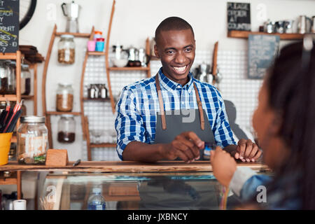 Smiling barista taking a credit card from a cafe customer Stock Photo