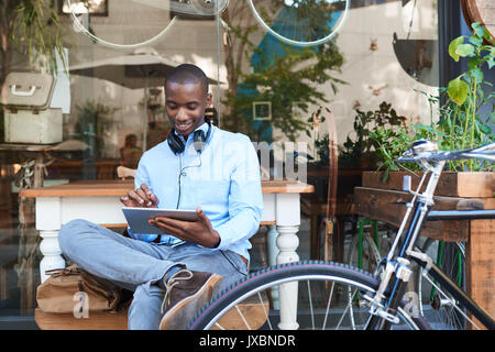 Young man browsing the internet at a sidewalk cafe Stock Photo