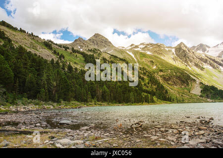 Clear river with rocks leads towards mountains lit by sunset Stock Photo