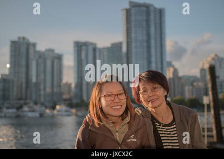 mother and daughter enjoying themselves together with a backdrop of city and sea. Stock Photo
