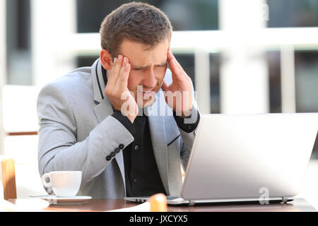 Tired executive suffering head ache working on line sitting in a coffee shop Stock Photo
