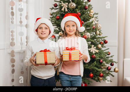 Cute little children with gift boxes near Christmas tree at home Stock ...