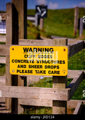 A sign warning of cliff edges, concrete structures and sheer drops, please take care sign at the Needles, Isle of Wight. Stock Photo